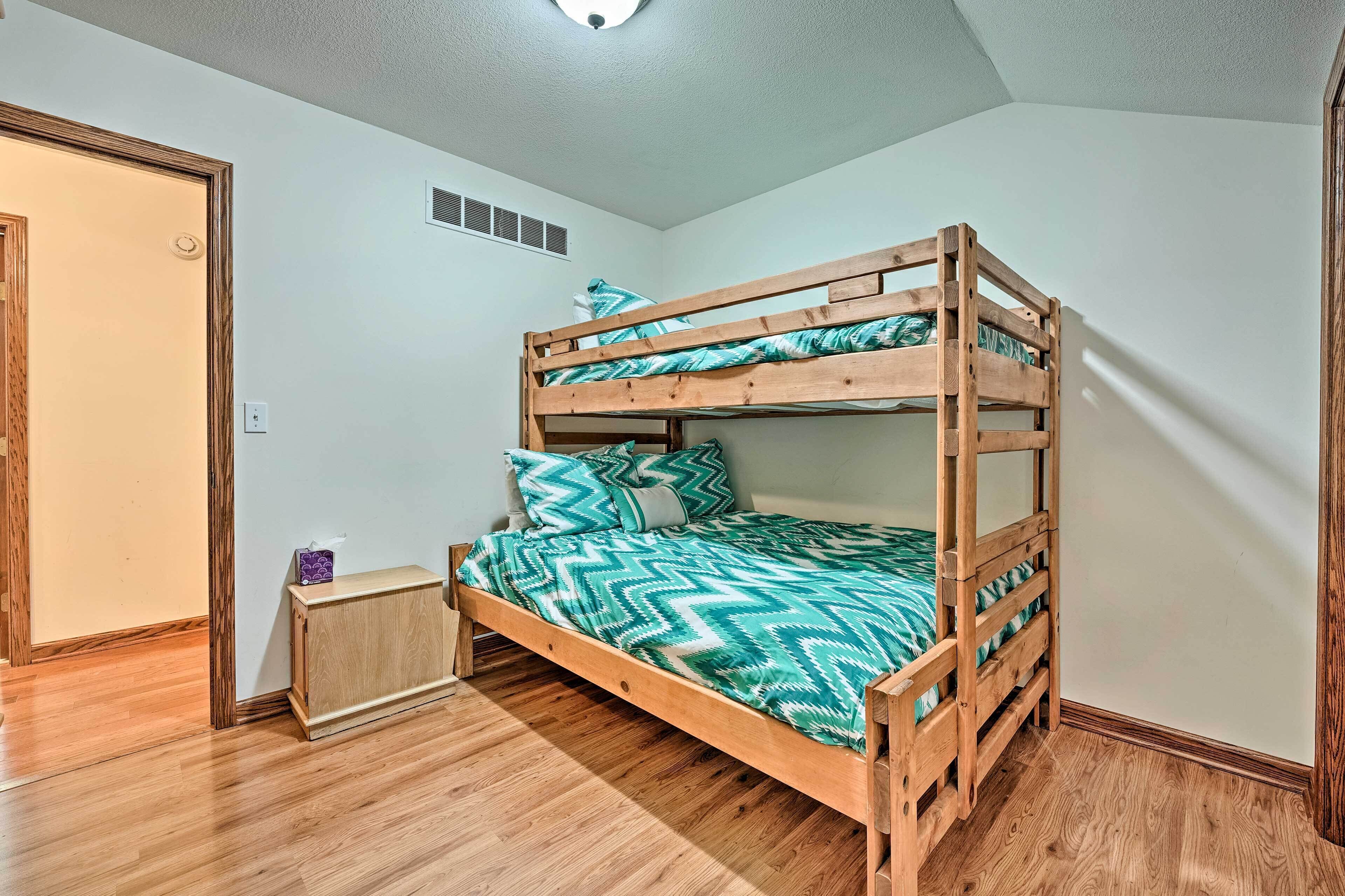 A bunk bed with a patterned bedspread, a bedside table, and a small cabinet.