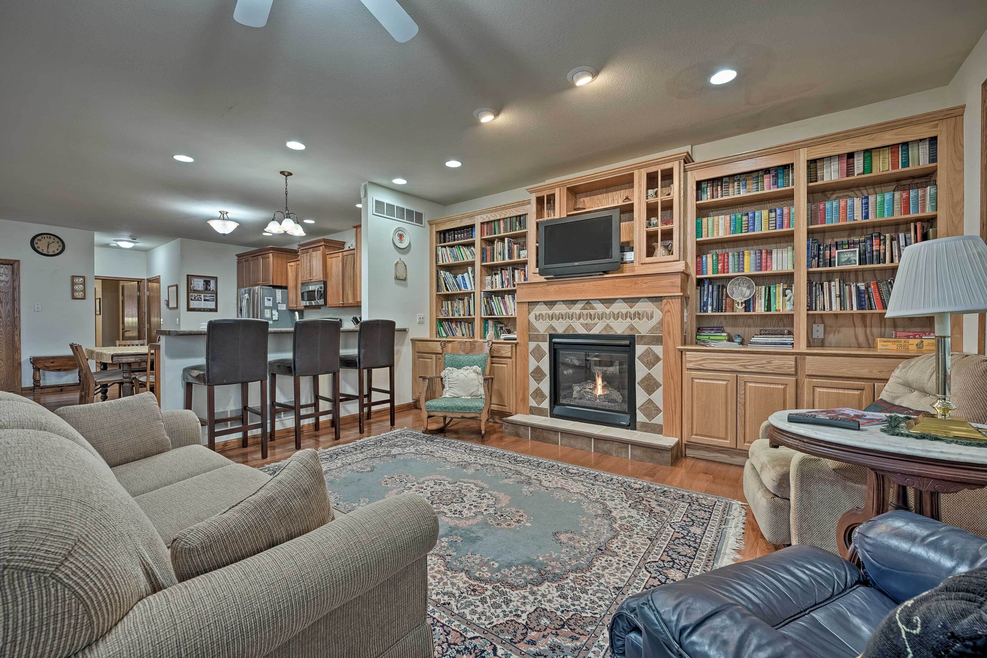 A living room with a fireplace, bookshelves, a television, and a dining area.