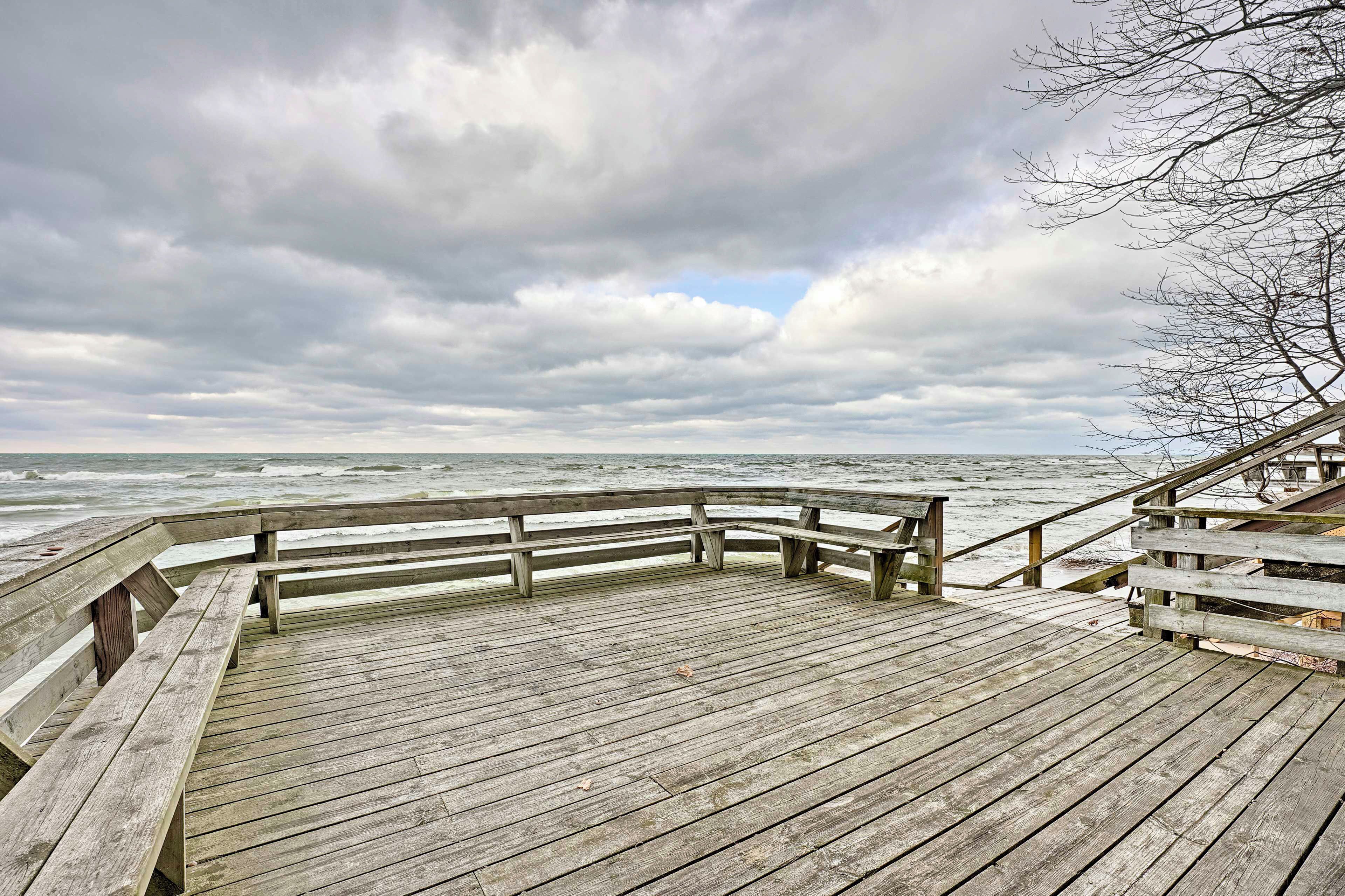 A wooden pier with benches and a railing overlooking the ocean.