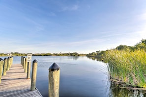 A wooden dock extending into calm water with a sign indicating the end of the ramp.