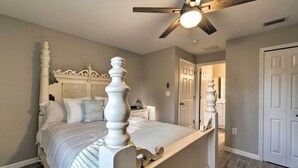 Un dormitorio con una cama grande, un ventilador de techo y una puerta que da a otra habitación.