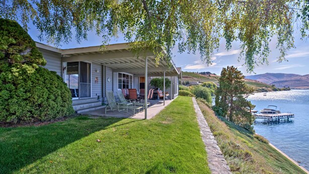 A house with a covered porch, a lawn, and a view of a lake with docks.