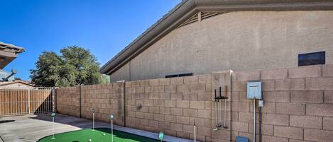 A miniature golf course with a brick wall and a clear sky.