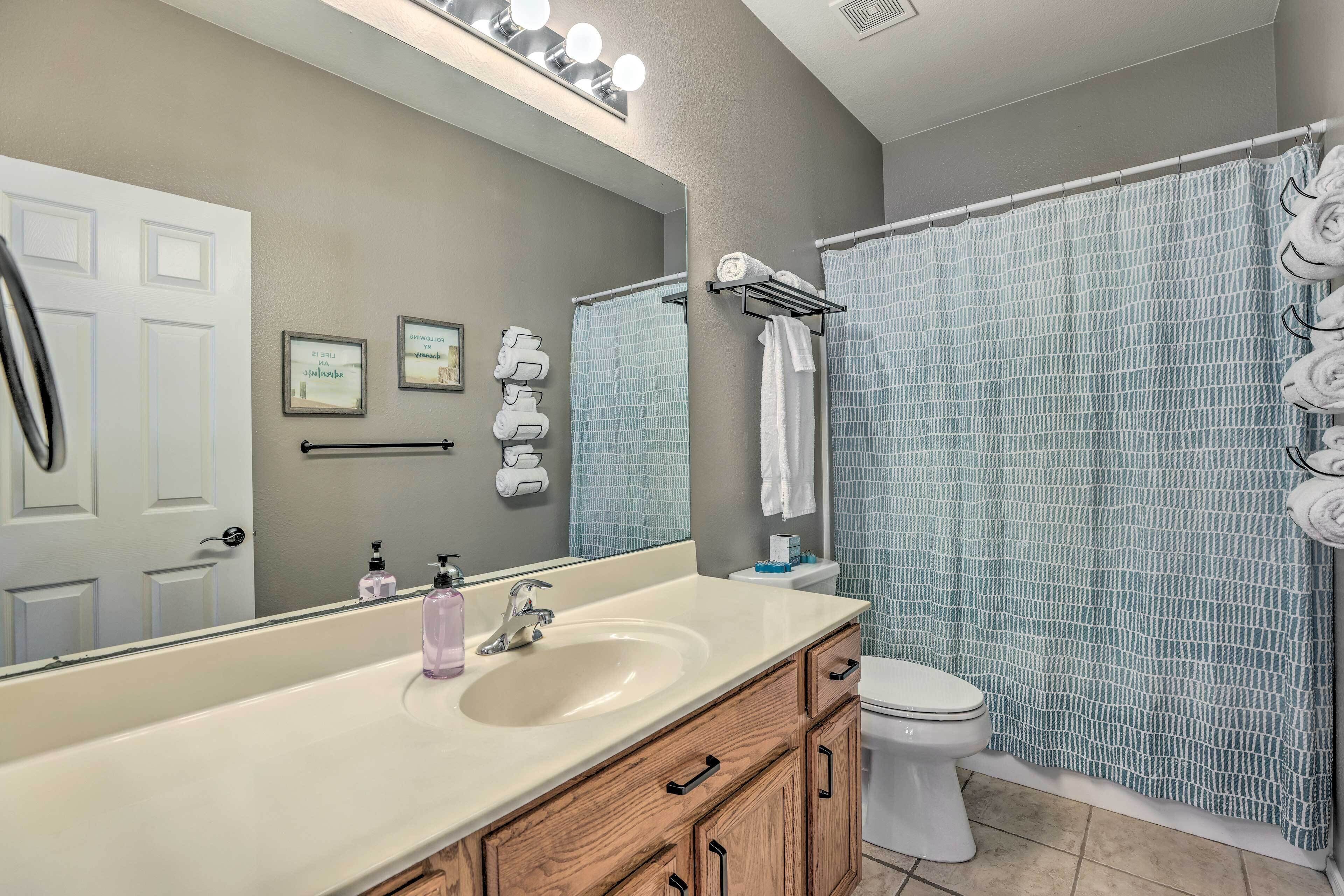 A bathroom with a large mirror, a sink, a toilet, and a shower curtain.
