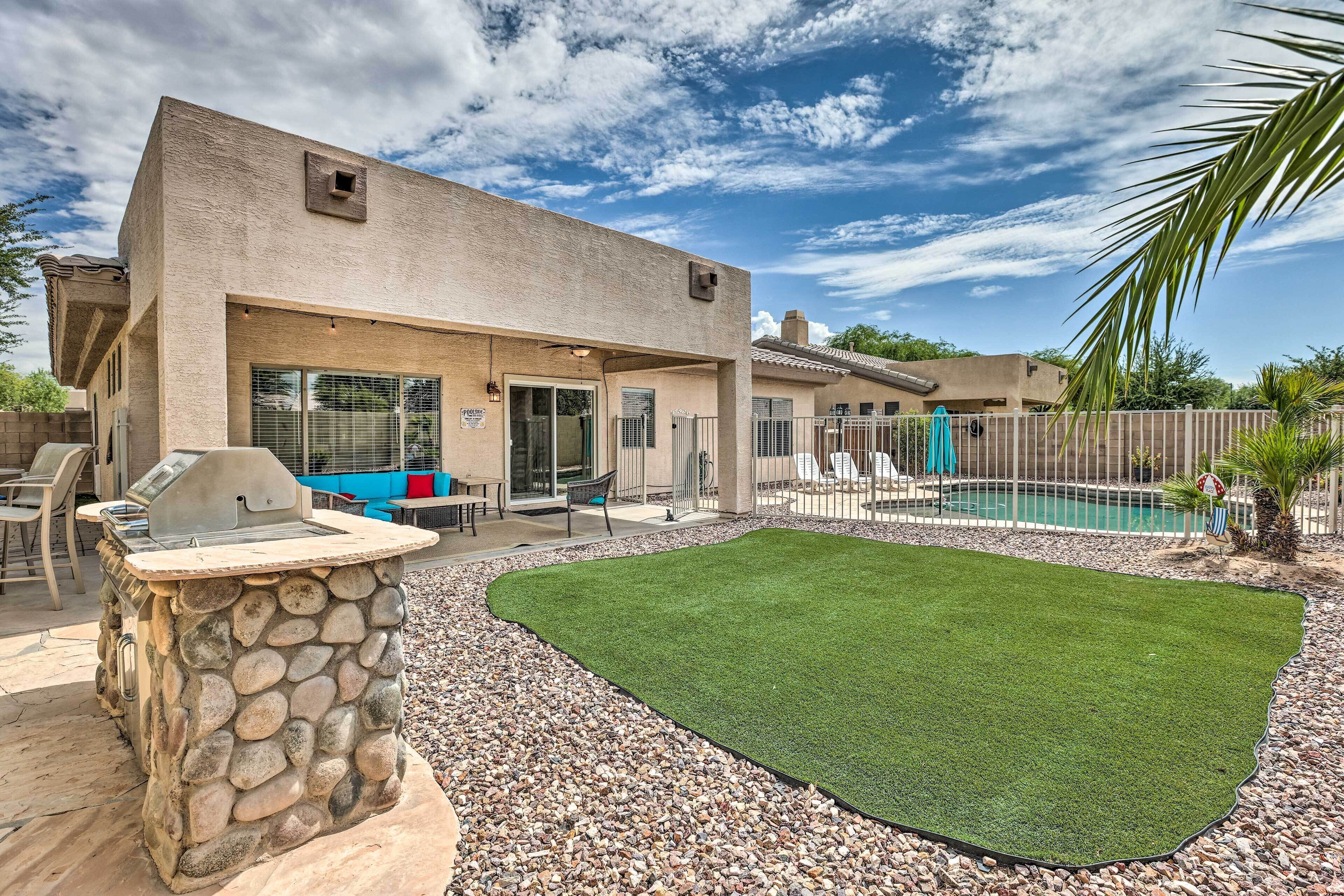 A house with a stone barbecue, a swimming pool, and a patio area.