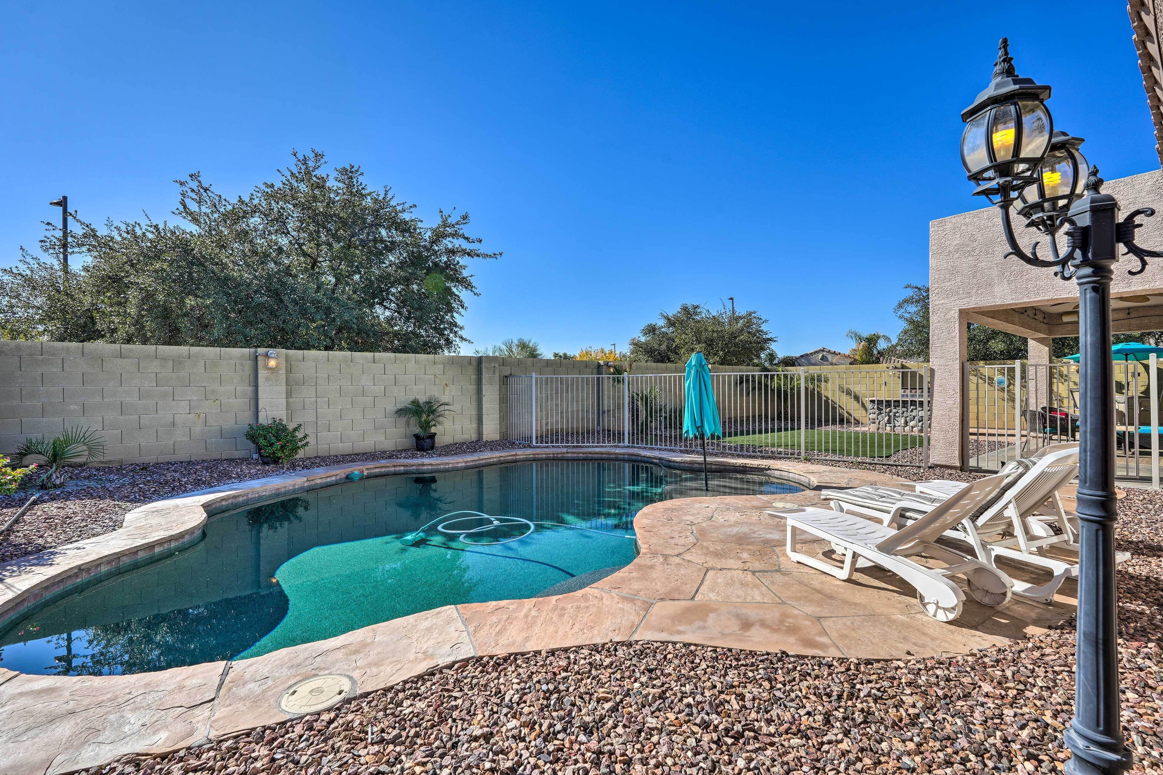 A swimming pool with lounge chairs and a pergola.