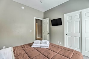 Una camera da letto con un letto, una TV a schermo piatto montata a parete e una porta.