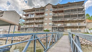A multi-story building with balconies and a wooden deck over water. - Lake & Poolside Fun! Water-view Camdenton Condo (Camdenton)
