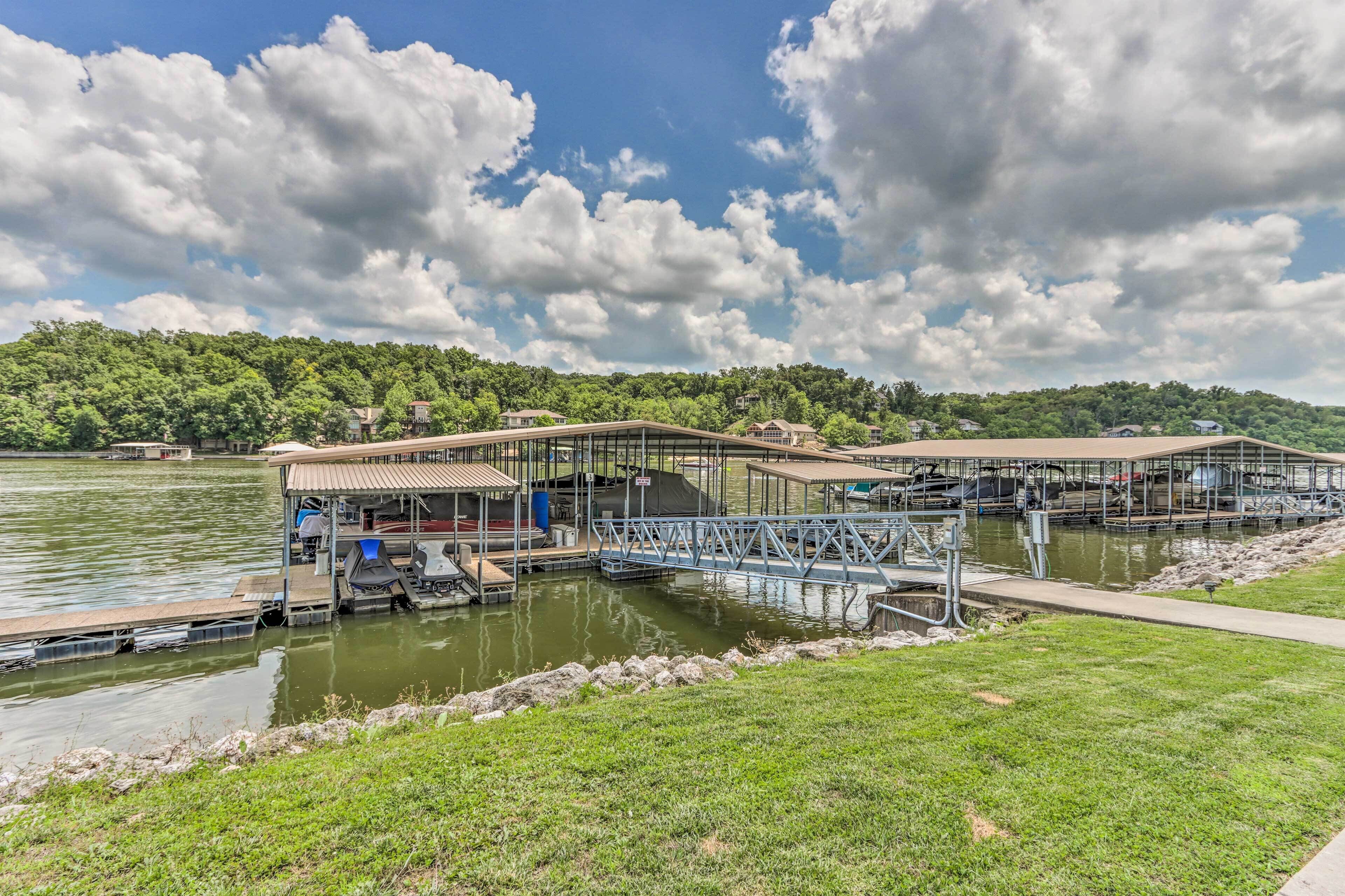 A lakeside dock with covered seating areas and a boat ramp.