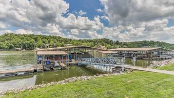A lakeside dock with covered seating areas and a boat ramp.