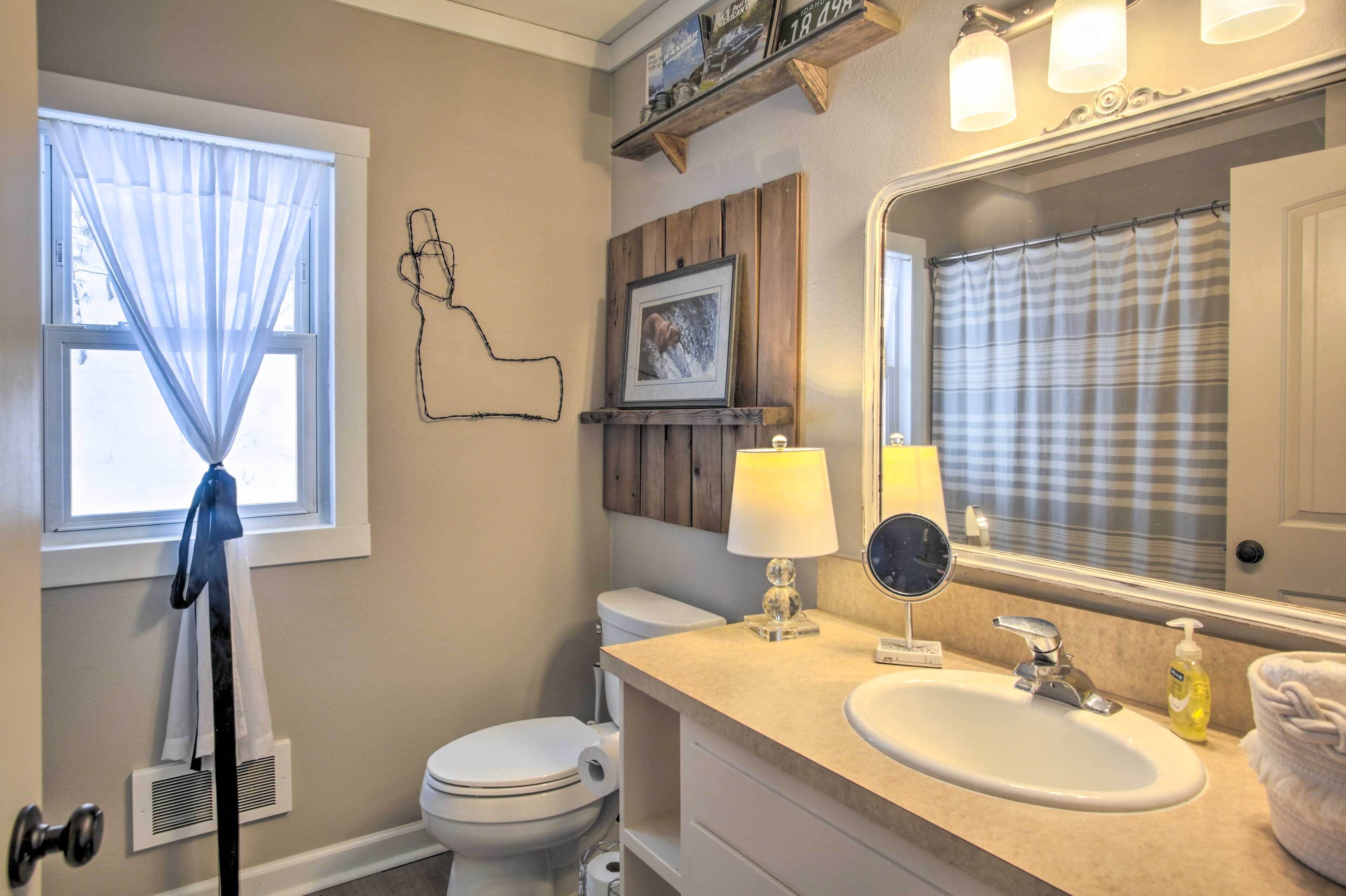 A bathroom with a toilet, sink, mirror, and towel rack.