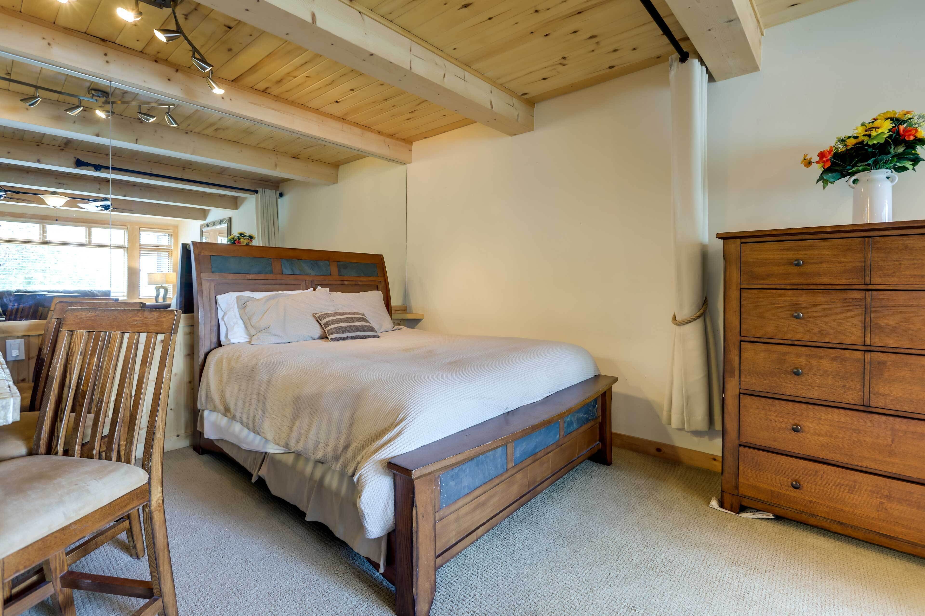 Une chambre à coucher avec un lit en bois, une commode en bois et une chaise.