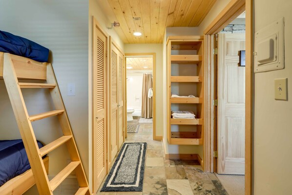 A narrow hallway with a wooden ladder, wooden shelving units, and a door leading to a bathroom. - Ski-in/ski-out Studio in Aspen Snowmass Ski Resort (Snowmass Village)