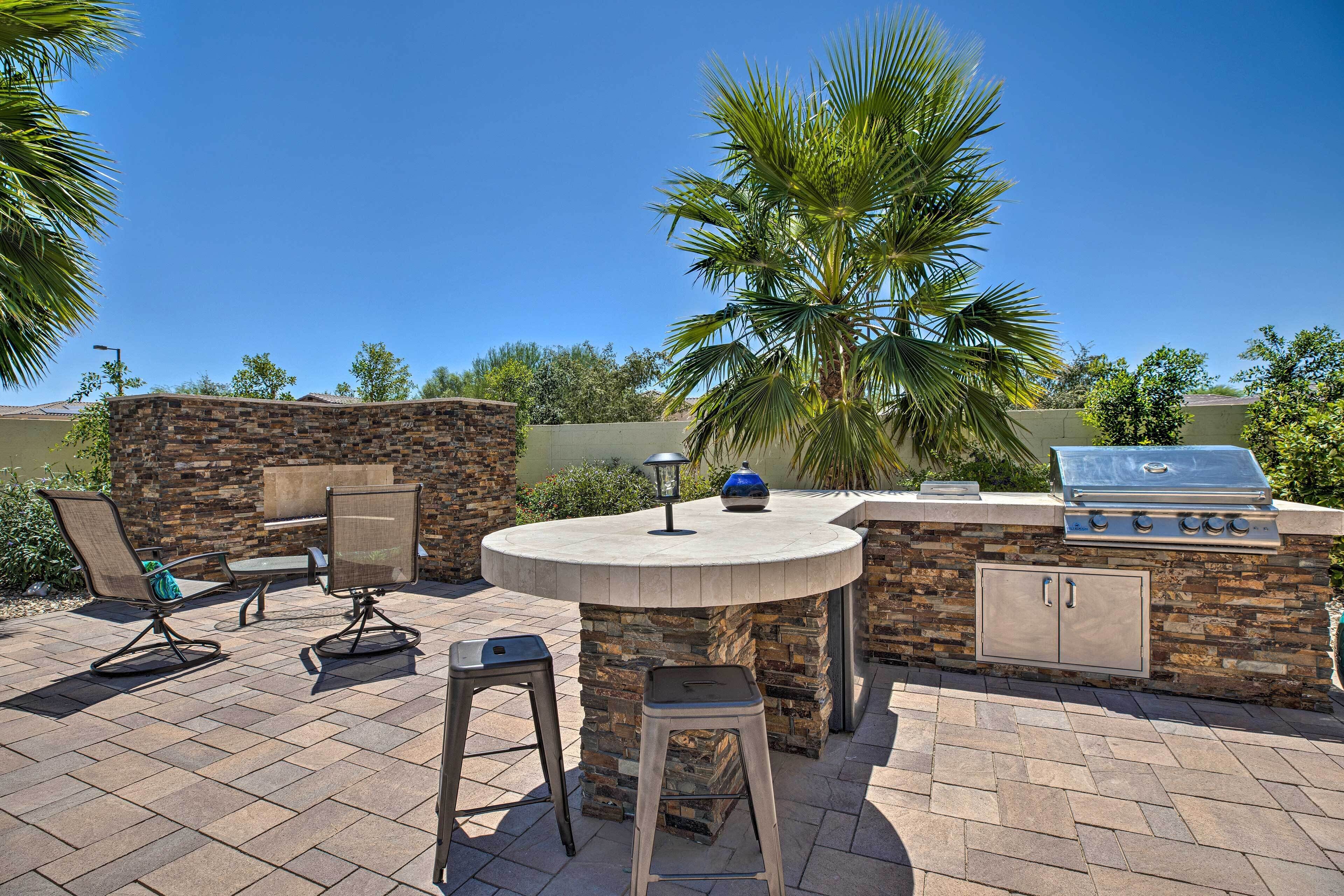An outdoor patio with a stone barbecue and seating area.