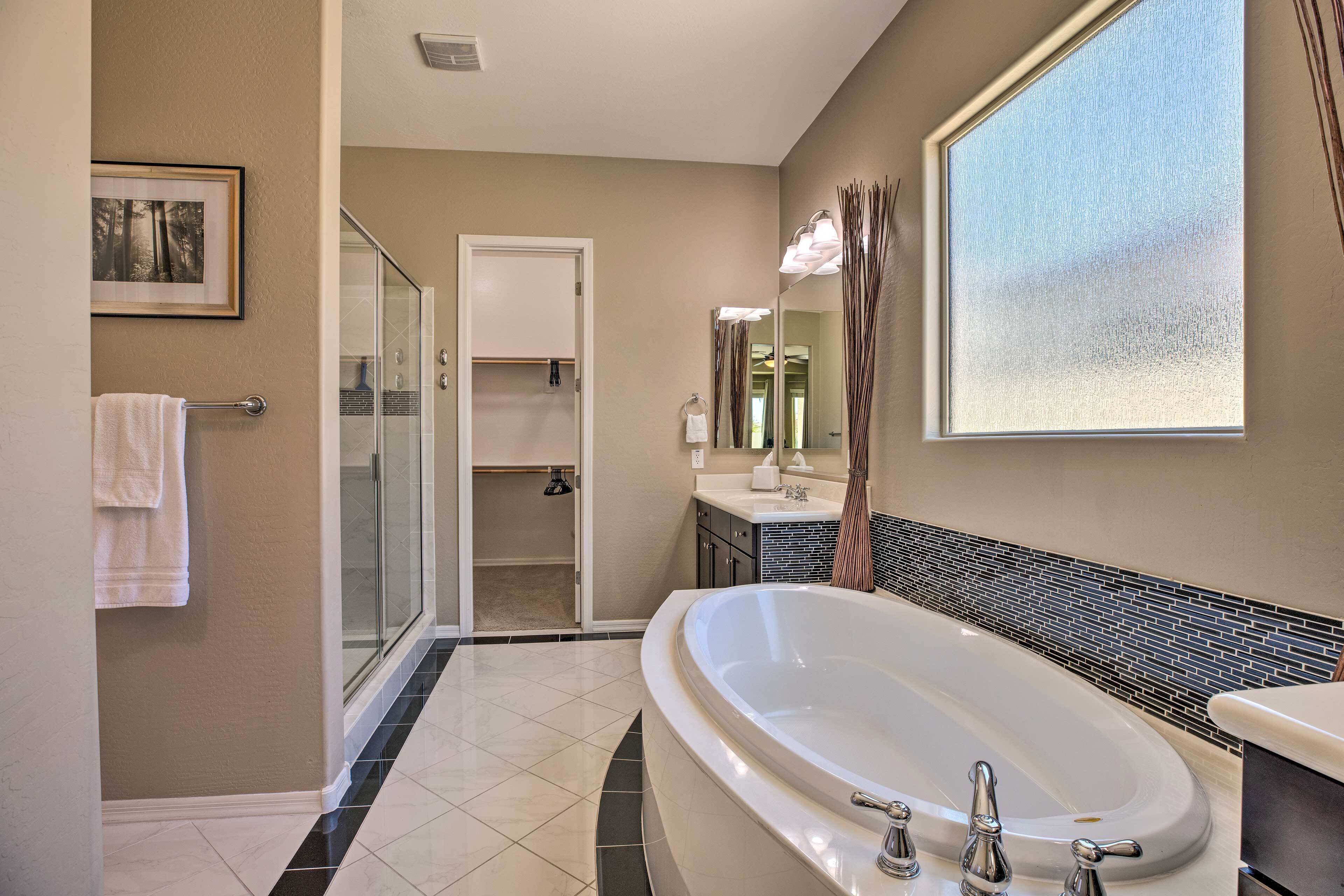 A modern bathroom with a large bathtub, a glass shower enclosure, and a vanity with a mirror.
