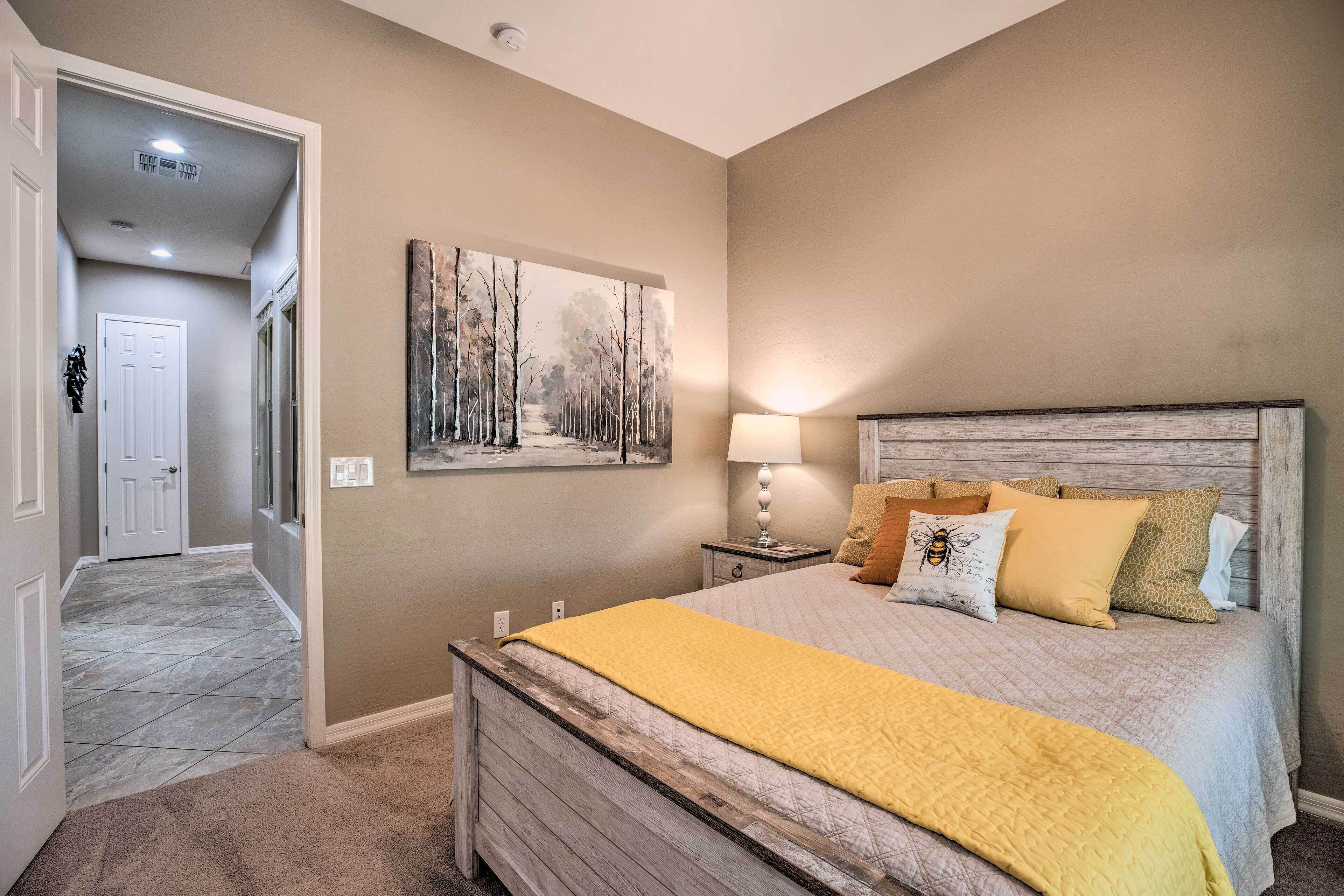 Un dormitorio con cama, mesita de noche, lámpara y un cuadro en la pared.