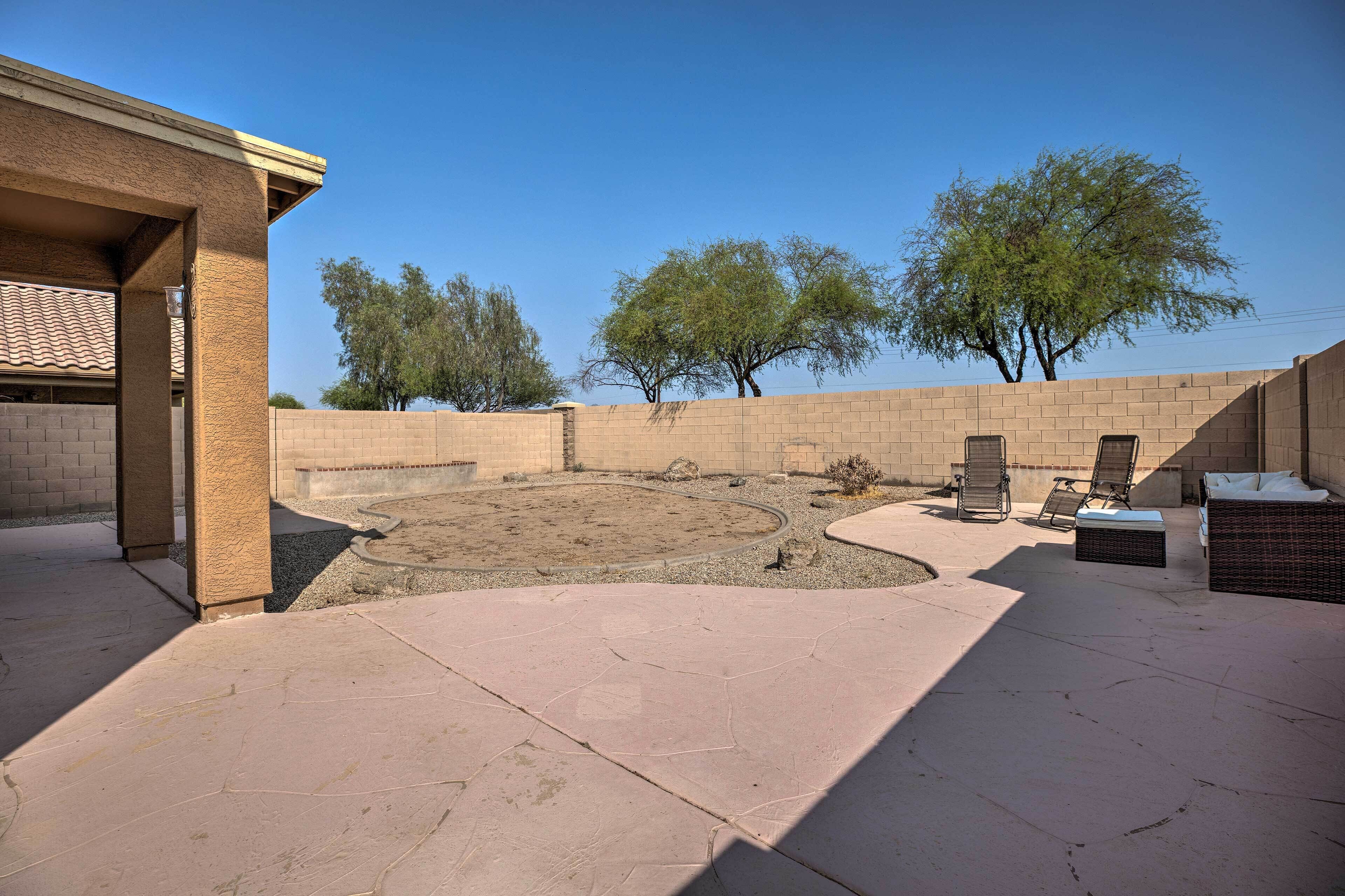 A backyard with a brick wall, a circular gravel area, and outdoor furniture.