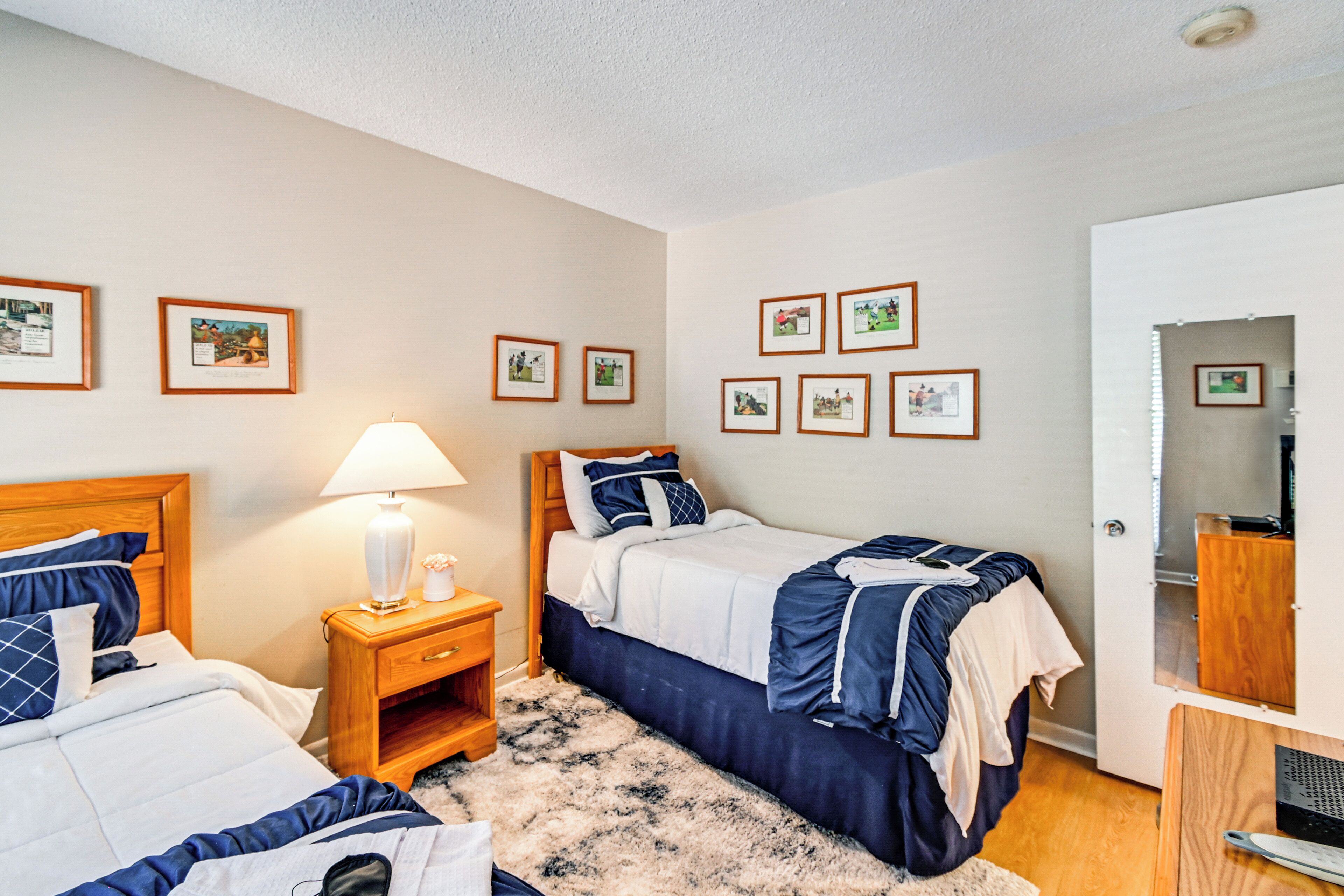 A bedroom with two beds, a nightstand with a lamp, and a wardrobe.