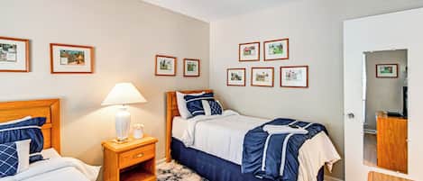 A bedroom with two beds, a nightstand with a lamp, and a wardrobe.