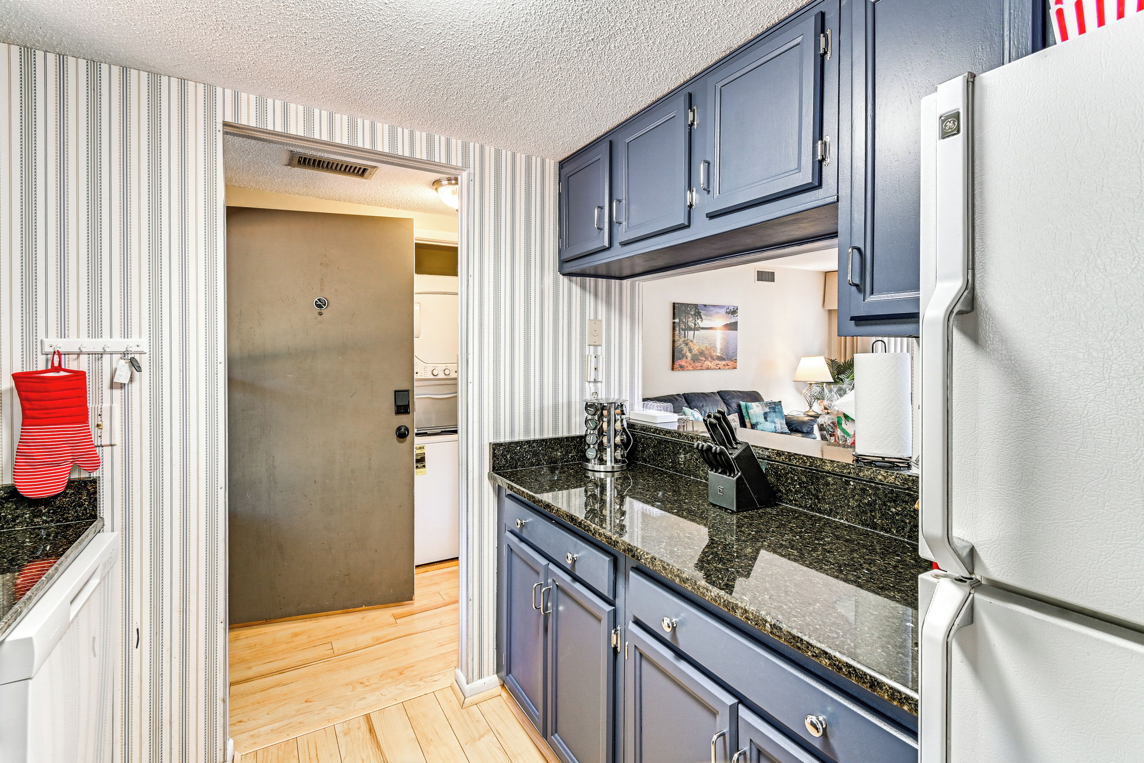 A kitchen with striped wallpaper, a refrigerator, a sink, and cabinets.