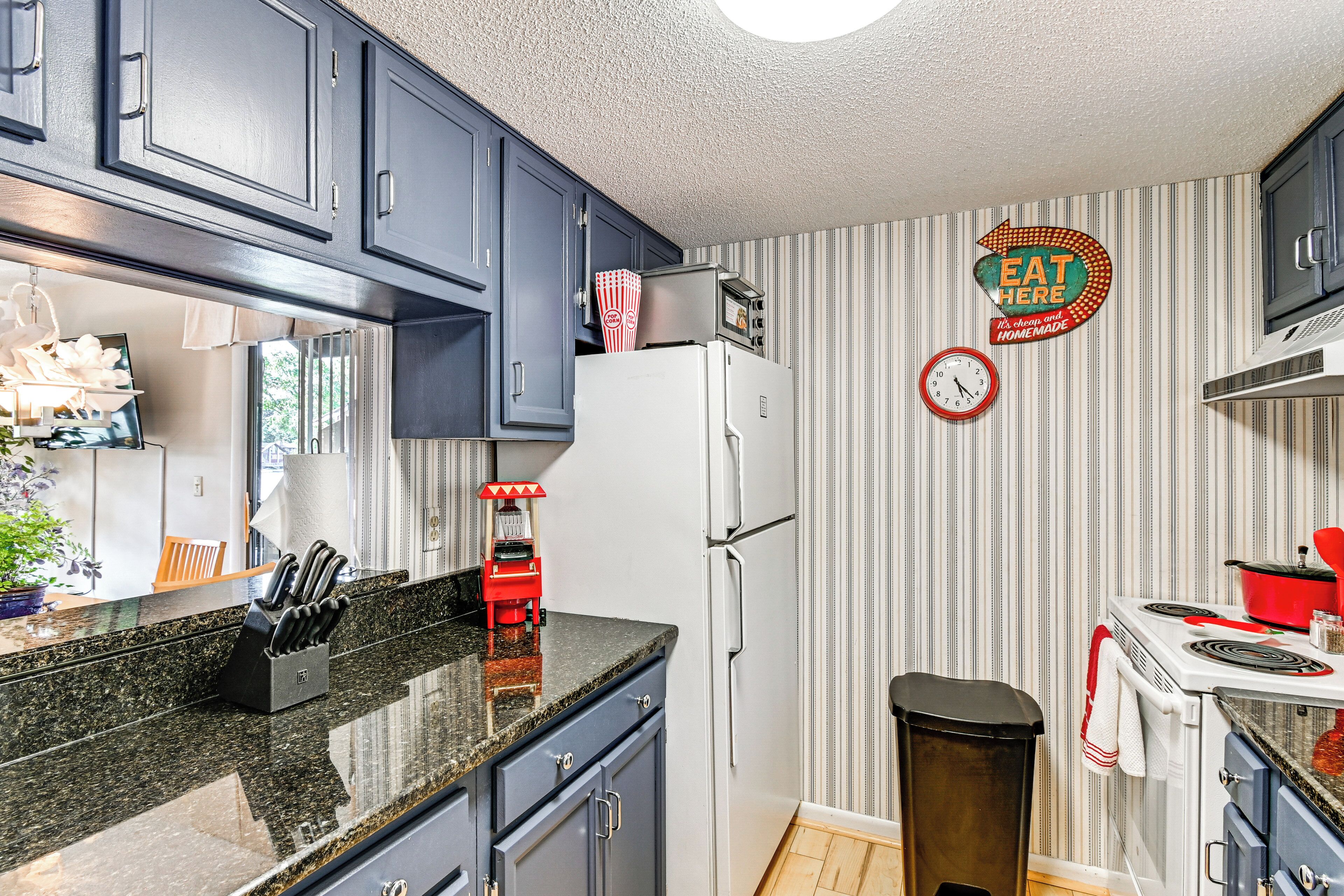A kitchen with dark blue cabinets, a white refrigerator, a stove, and a clock on the wall.