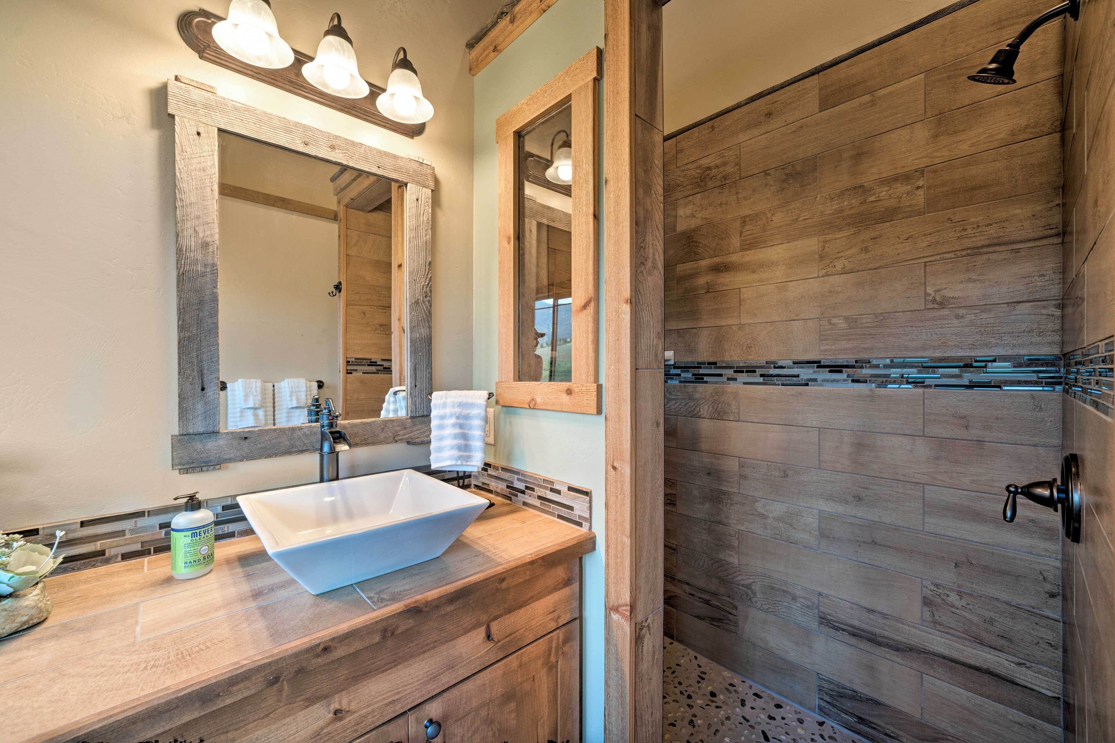 A bathroom with a wooden vanity, a large mirror, and a shower area with wooden walls.
