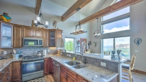 A spacious kitchen with wooden cabinets, a granite countertop, a built-in oven, and a large island with a sink. - Hot Tub & Mtn View! Cripple Creek Retreat (Cripple Creek)