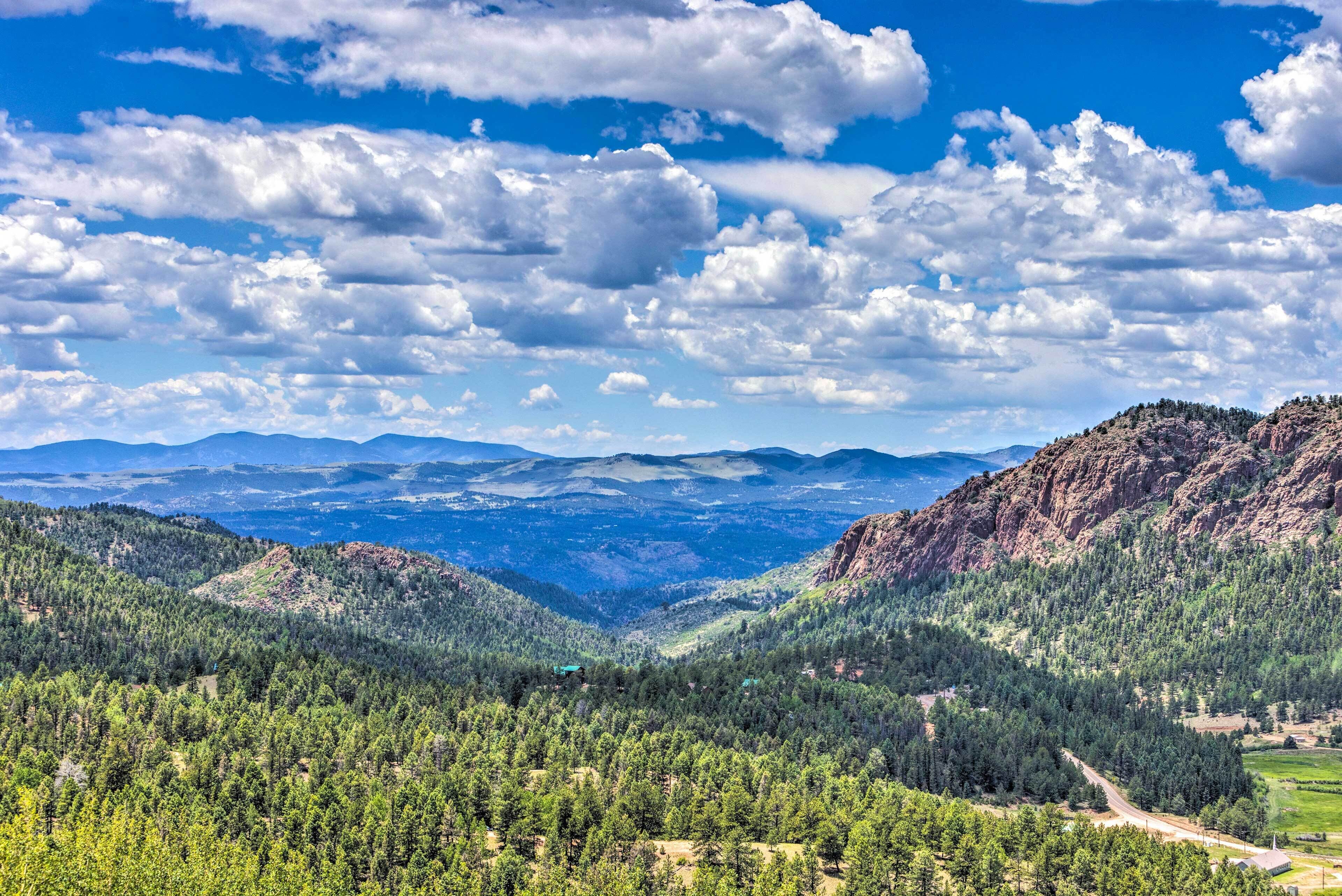 A mountainous landscape with dense forests and a clear sky.