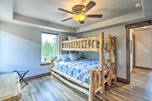 A bunk bed with a wooden frame and a ceiling fan above.
