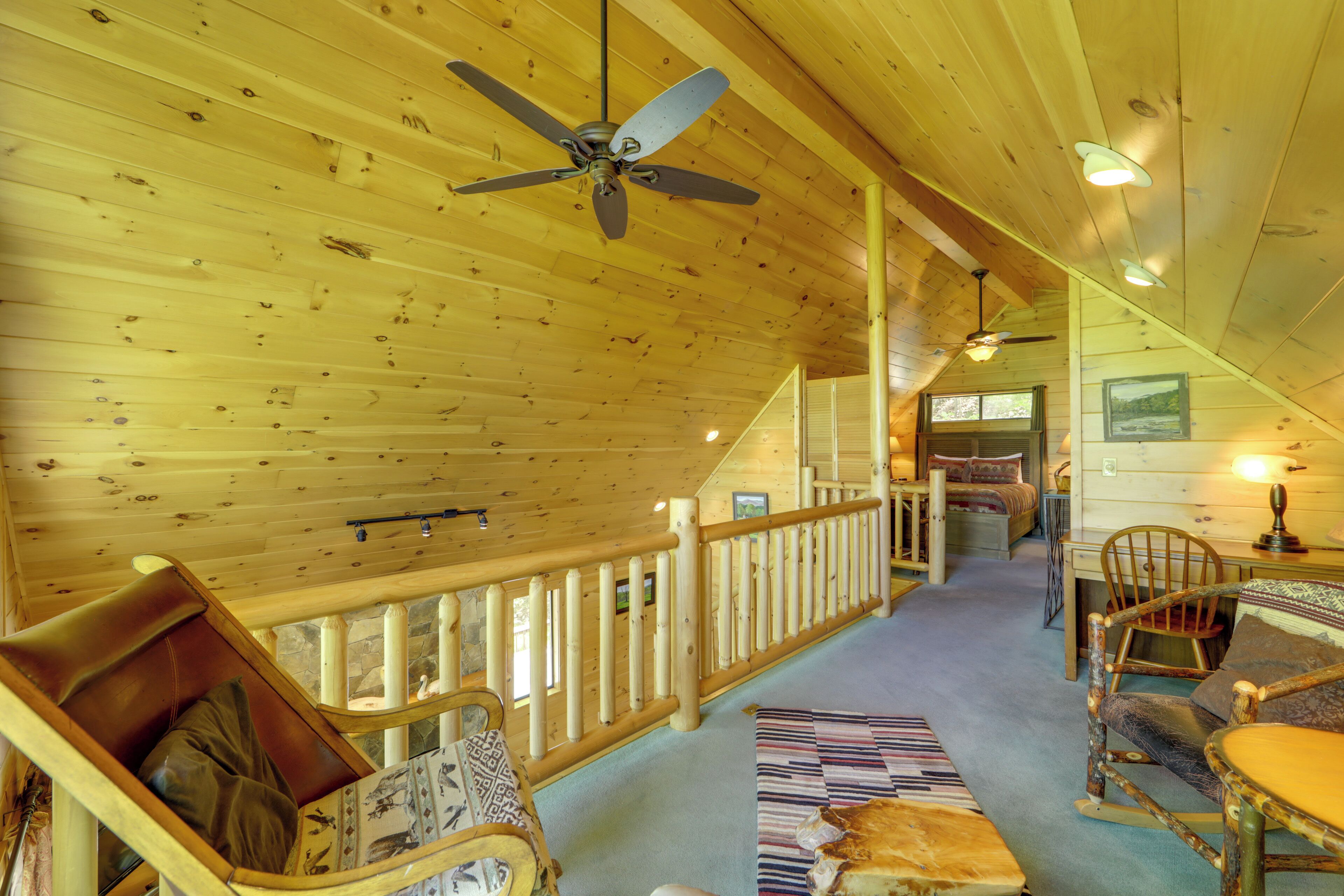 Un intérieur en bois avec un ventilateur de plafond, un escalier et un lit doté d’une tête de lit.