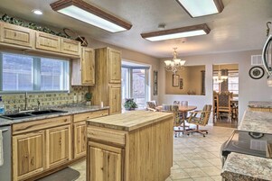 Una cocina con armarios de madera, encimera de granito y una isla central. Hay una zona de comedor con una mesa y sillas.