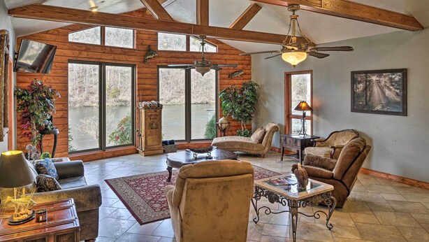 A spacious living room with wooden beams, large windows, and a fireplace. - Waterfront Hollister Retreat w/ Dock & Game Room! (Hollister)