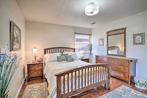 Un dormitorio con una cama de madera, mesitas de noche, un aparador y un espejo grande.
