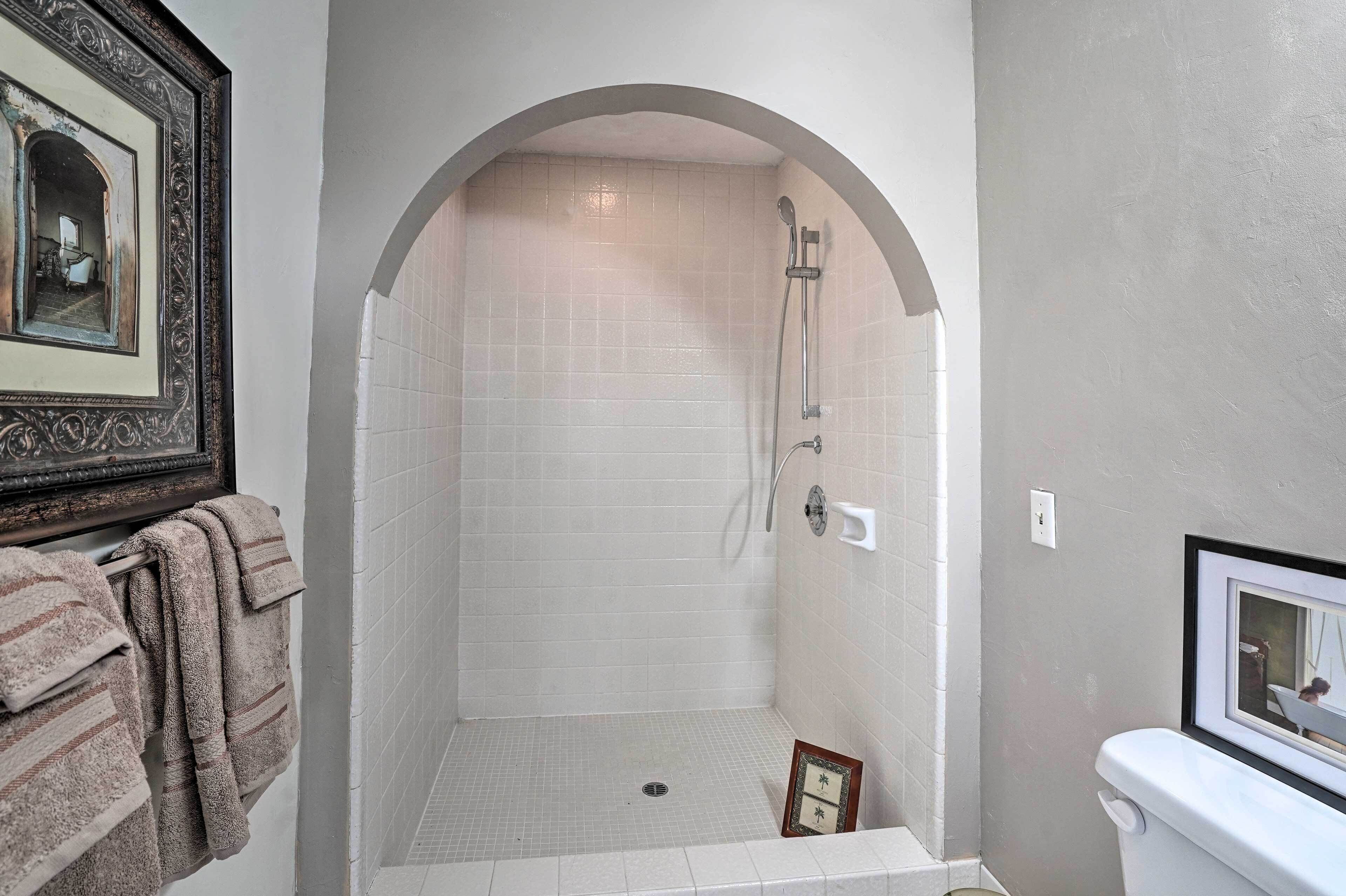 A bathroom with a shower, tiled walls, a framed mirror, and a towel rack.