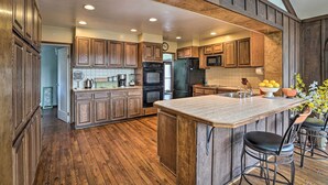 A kitchen with wooden cabinets, a central island, and a large window. - Hot Tub & Views: Spacious Getaway on Rogue River (Grants Pass)