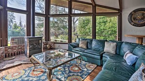 A cozy living room with a green leather sofa, a glass coffee table, and a fireplace. - Hot Tub & Views: Spacious Getaway on Rogue River (Grants Pass)