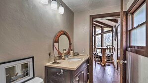 A bathroom with a large mirror, two sinks, and a wooden door leading to a dining area. - Hot Tub & Views: Spacious Getaway on Rogue River (Grants Pass)