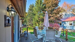 A wooden deck with outdoor furniture and a welcome mat. - Walk to Beach! Bolton Landing Cottage w/ Deck (Bolton Landing)