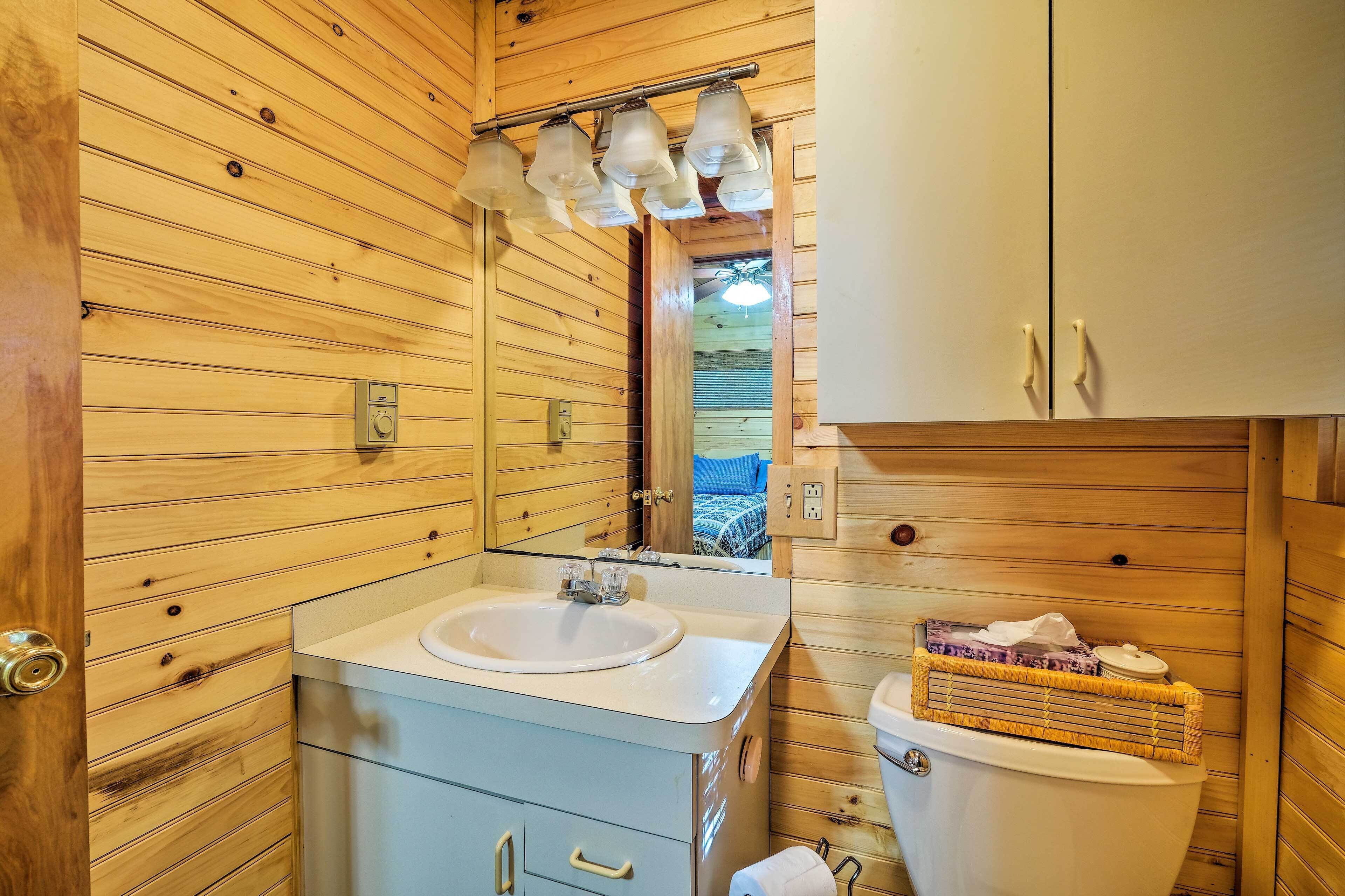 A wooden cabin bathroom with a sink, mirror, and toilet.