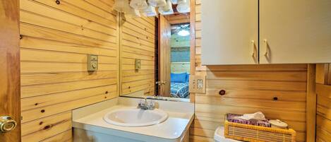 A wooden cabin bathroom with a sink, mirror, and toilet.