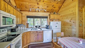 A wooden cabin kitchen with a central island, a refrigerator, a microwave, a stove, and a sink. - Walk to Beach! Bolton Landing Cottage w/ Deck (Bolton Landing)
