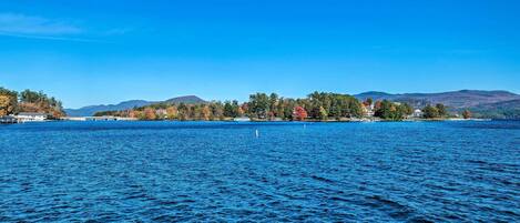 A lake with a clear view of a shoreline with buildings and trees.