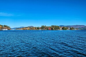 A lake with a clear view of a shoreline with buildings and trees. - Walk to Beach! Bolton Landing Cottage w/ Deck (Bolton Landing)