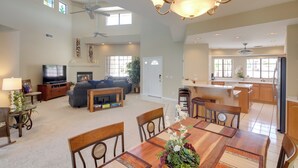 A spacious living room with a large dining table, a TV, and a kitchen area with wooden cabinets. - 3 Mi to Lake Havasu: Luxe Home w/ Pool & Spa! (Lake Havasu City)