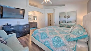 Ein Schlafzimmer mit einem großen Bett, einem an der Wand montierten Fernseher, einem Deckenventilator und einer Kommode.