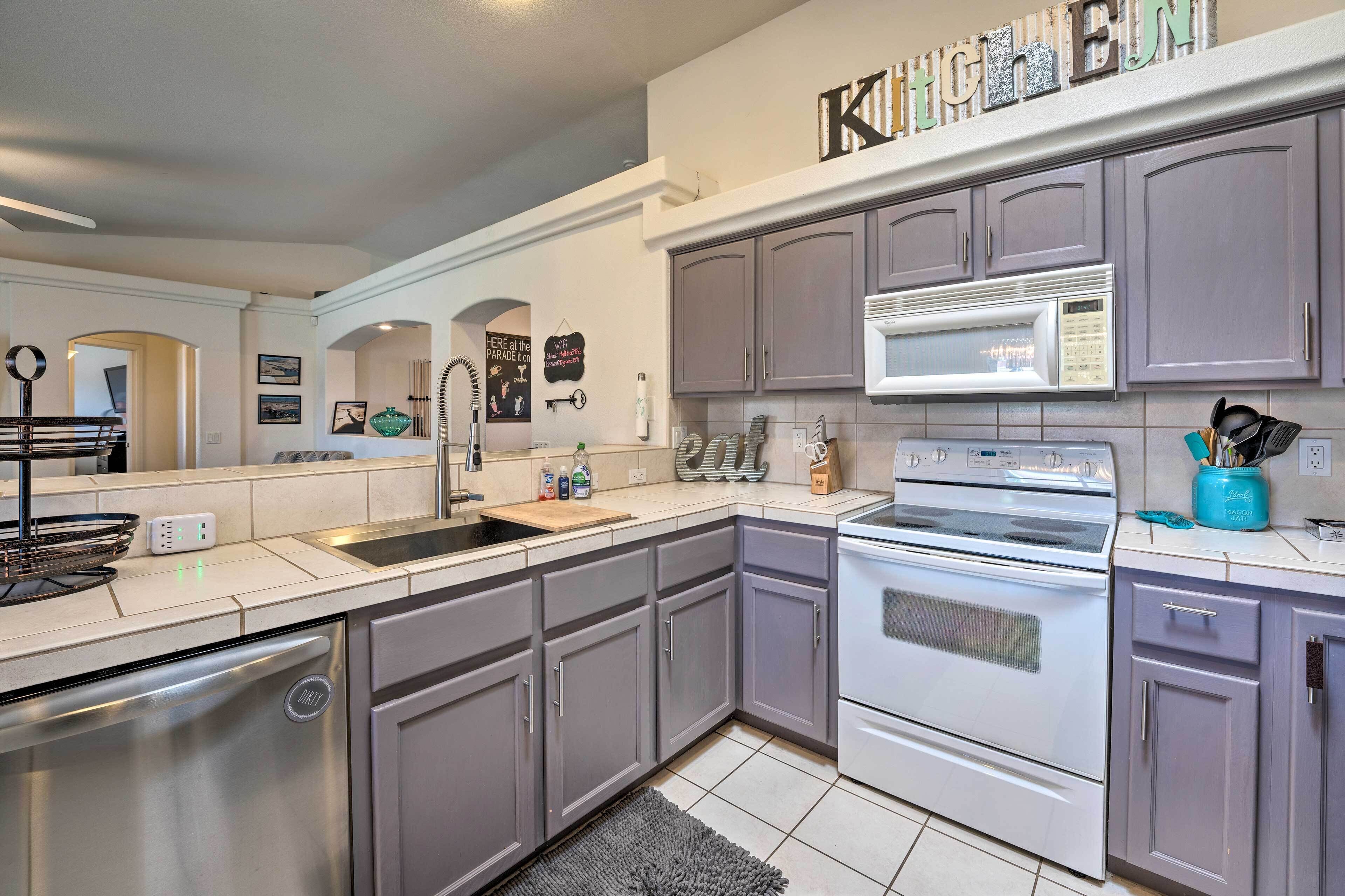 A modern kitchen with grey cabinets, stainless steel appliances, and a microwave.