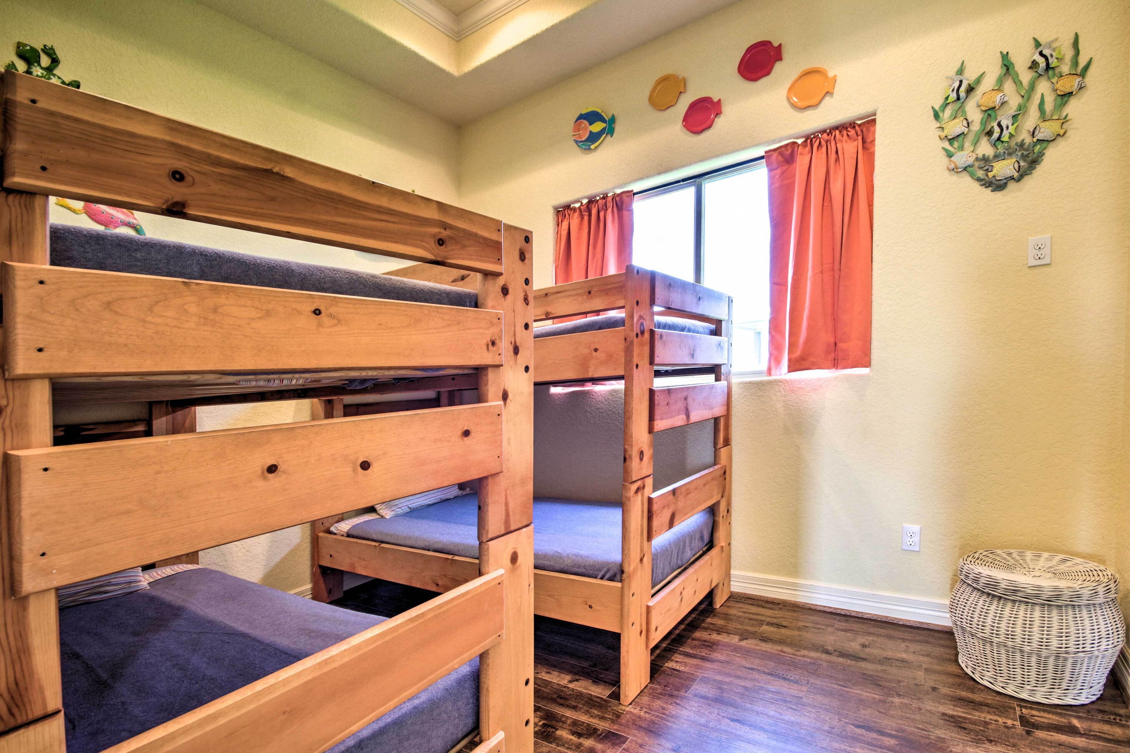 Une chambre avec un lit superposé, une fenêtre, des rideaux orange et des décorations murales.