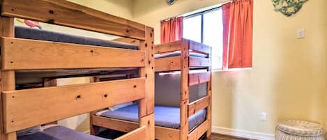 Une chambre avec un lit superposé, une fenêtre, des rideaux orange et des décorations murales.