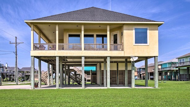 A two-story house with a balcony, a covered porch, and a staircase leading to the upper floor. - Dog-friendly Casa Sol House in Crystal Beach! (Port Bolivar)