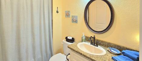 A bathroom with a toilet, sink, and mirror.